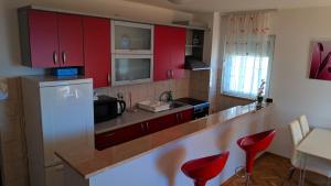 a kitchen with red cabinets and red stools at Apartman Baška Voda in Baška Voda