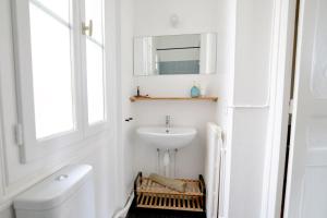 La salle de bains blanche est pourvue d'un lavabo et d'un miroir. dans l'établissement PALMA Cozy - minutes aways from everything!, à Biarritz