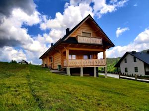 a wooden cabin on a hill with a green field at Domki góralskie na Podhalu Zakopane in Tokarnia