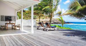 a porch with chairs and a table and the ocean at Dream Villa Lorient 659 in Saint Barthelemy