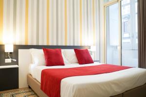 una camera da letto con un letto con cuscini rossi e bianchi di Hotel Cimarosa a Napoli