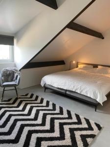 1 dormitorio con 1 cama, 1 silla y 1 alfombra en Maashuys, en Lanaken