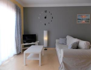 a living room with a couch and a clock on the wall at Family Heaven - No Stress Holidays in El Cotillo