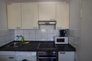 a kitchen with white cabinets and a sink and a microwave at Apartment Wangen in Stuttgart