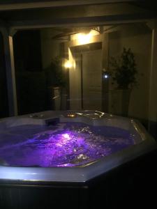 - une baignoire violette avec des lumières dans la chambre dans l'établissement Villa Tamara Country & Spa Suites, à Montefiore Conca