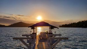 uma doca com um gazebo sobre a água ao pôr-do-sol em Pousada Mestre Augusto em Angra dos Reis