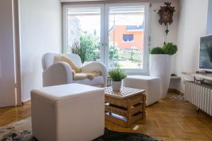 ein Wohnzimmer mit weißen Stühlen und einem Fenster in der Unterkunft Ferienwohnung Hedwig in Breitnau
