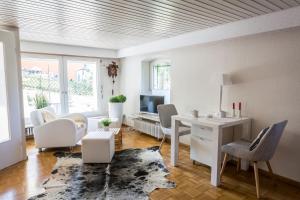 ein weißes Wohnzimmer mit einem Schreibtisch und Stühlen in der Unterkunft Ferienwohnung Hedwig in Breitnau