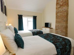 una camera da letto con due letti e un muro di mattoni di Beech Cottage a Filey