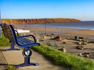 una panchina blu seduta sul lato di una spiaggia di Beech Cottage a Filey