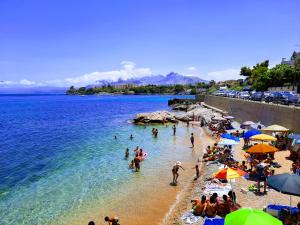 a crowd of people on a beach with umbrellas at Seafront House Gabbiano Blu in Santa Flavia