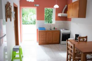 cocina con paredes rojas, mesa y fregadero en Elena's Family Apartments, en Leonidio