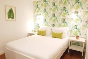 1 dormitorio con cama blanca y papel pintado tropical en InLoveApartments - Typical Alfama Balcony, en Lisboa