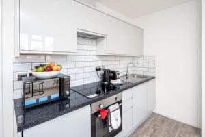 a white kitchen with a bowl of fruit on the counter at Skyline Serviced Apartments - Vauxhall in London