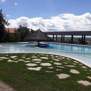 a large swimming pool with a grass umbrella in the middle at Flat Monte Castelo Gravatá in Gravatá