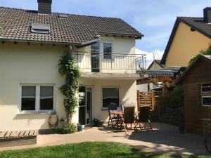 ein Haus mit einer Terrasse mit einem Tisch und Stühlen in der Unterkunft Ferienhaus Moselglück - kostenlose ÖPNV-Nutzung inbegriffen in Bernkastel-Kues