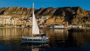 ein Segelboot, das mit einem Berg im Wasser schwimmt in der Unterkunft Moon Hotel & SPA. in Aguadulce