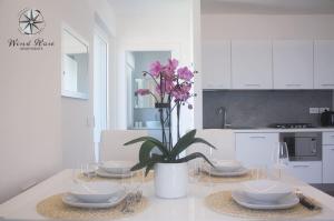 a white kitchen with a table with glasses and a plant at Wind Rose Apartments in Nago-Torbole