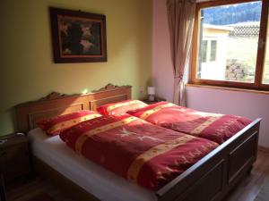 ライト・イム・アルプバッハタールにあるWohlfühlchalet Tirolのベッドルーム1室(赤いシーツ付きのベッド1台、窓付)