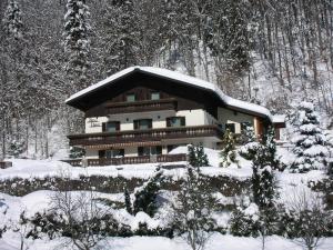 a house covered in snow in a forest at Haus Ebner in Sankt Gilgen