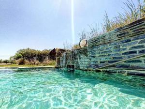 une piscine d'eau bleue à côté d'un mur de briques dans l'établissement Lusitaurus, à Montoito