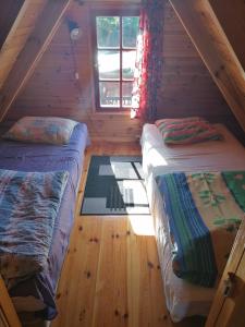 - une chambre avec 2 lits dans une cabane en rondins dans l'établissement Domek Jantar, à Jantar