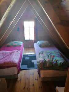 2 Betten in einem Dachzimmer mit Fenster in der Unterkunft Domek Jantar in Jantar