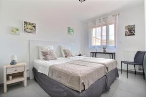 a white bedroom with a large bed with a window at O de mer D101 in La Ciotat