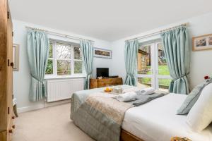 ein Schlafzimmer mit einem Bett und zwei Fenstern in der Unterkunft Mews Hill, 5 bedroom New Forest Holiday Cottage in Fordingbridge