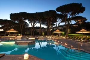 a swimming pool with chairs and umbrellas at night at SUITE 225 Golf H PROMO SERVICE SRL in Castiglione della Pescaia