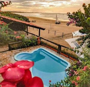 a swimming pool next to a beach with the ocean at Pousada Vira Sol in Trairi
