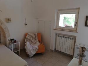 a bedroom with an orange chair and a window at Marinelli Guest House in Cisternino