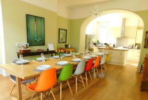 Substantial 6 bed House in Christchurch Dorset في كرايستشيرش: غرفة طعام مع طاولة طويلة مع كراسي ملونة