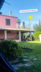 una casa rosa con el sol en el cielo en Agriturismo Santu Marcialis, en Dolianova