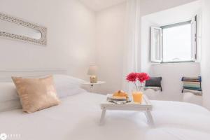 a white bedroom with a white bed and a table with food on it at Window To Heaven in Lisbon