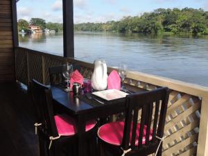 - une table avec des chaises roses et une vue sur la rivière dans l'établissement Ecolodge Luna del Rio, à El Castillo de La Concepción