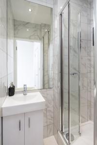a white bathroom with a sink and a shower at Skyline Serviced Apartments - Vauxhall in London