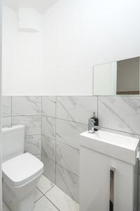 a white bathroom with a toilet and a sink at Skyline Serviced Apartments - Vauxhall in London