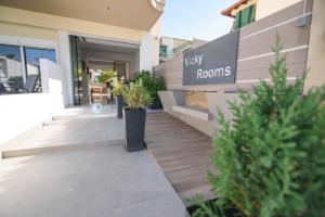 a building with a view rooms sign and plants at Vicky Rooms in Paralia Dionysiou