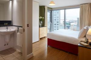 una camera d'albergo con un letto, un lavandino e una finestra di Marlin Aldgate Tower Bridge a Londra