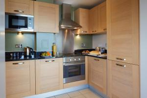 a kitchen with wooden cabinets and a stove top oven at Marlin Aldgate Tower Bridge in London