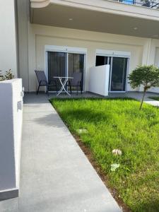 a patio with a table and chairs in the grass at Vicky Rooms in Paralia Dionysiou