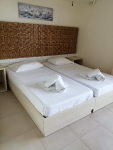 uma grande cama branca com duas toalhas brancas em Pantheon Beach Hotel em Olympiakí Aktí