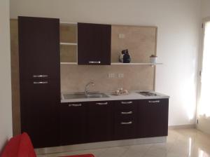 una cucina con armadi neri e lavandino di casa La sorgente di Carlo Magno a Otranto