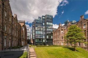 a group of buildings with a grassy yard in front at Quartermile Central Apartment in Edinburgh