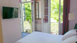 1 dormitorio con 1 cama y puerta corredera de cristal en Hôtel Confort 09 ou HC-09, en Tarascon-sur-Ariège