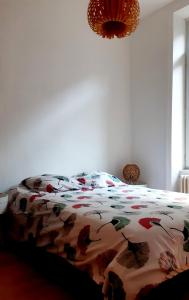 un letto con un piumone colorato in una camera da letto di La Villa des Thermes a Le Mont-Dore