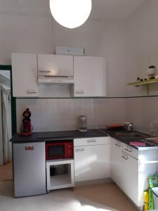 a kitchen with white cabinets and a red microwave at La Villa des Thermes in Le Mont-Dore