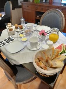 a table with a plate of bread and orange juice at Chambres d'Hôtes La Vigneronne in Senouillac