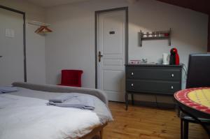 een slaapkamer met een bed, een dressoir en een rode stoel bij Chambres d'Hôtes La Vigneronne in Senouillac